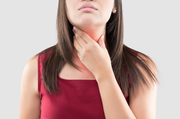 Ασιάτισσα με πονόλαιμο ή θυρεοειδή αδένα στο γκρίζο φόντο. Οξεία παλινδρόμηση ή Heartburn, πόνος στο λαιμό, άνθρωποι έννοια πρόβλημα του σώματος - Φωτογραφία, εικόνα