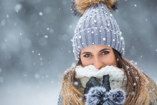 Portrait of young beautiful woman in winter clothes and strong snowing. - Photo, Image