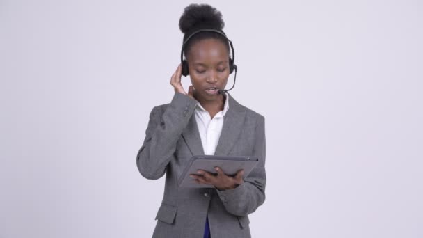 Young stressed African businesswoman as call center representative using digital tablet - Felvétel, videó