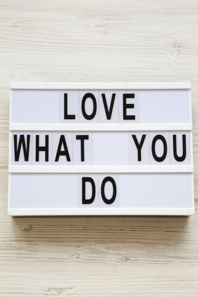 Современная доска с надписью "Любите то, что вы делаете" на белой деревянной поверхности, вид сверху. Бизнес-концепция. Сверху, плоский, над головой
.  - Фото, изображение