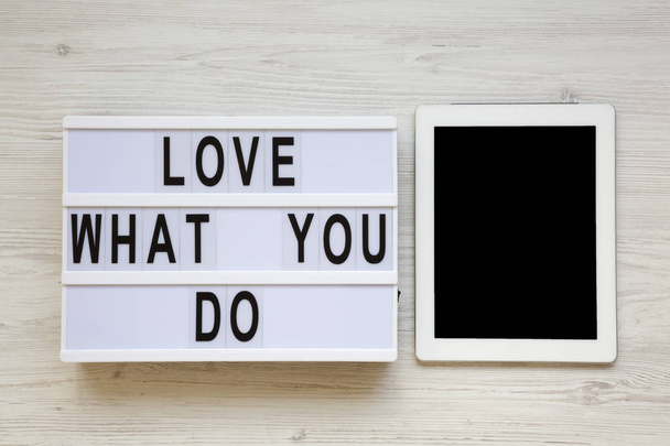Placa moderna com texto 'Amo o que você faz', tablet sobre fundo de madeira branca, vista superior. Conceito de negócio. De cima, flat-lay, sobrecarga
.  - Foto, Imagem