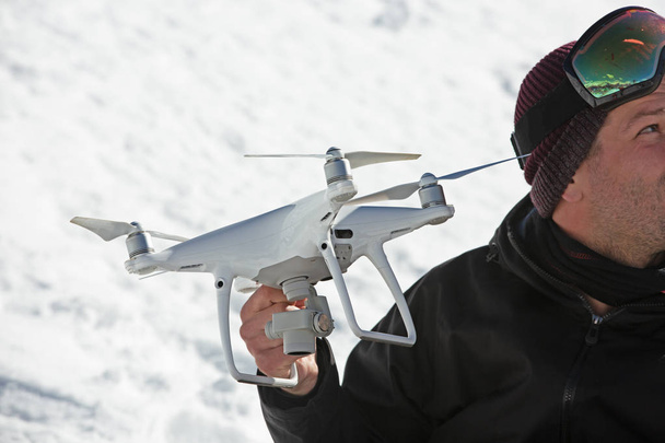 una mano de hombre sosteniendo un cuadrohelicóptero profesional sobre el fondo de un campo cubierto de nieve
. - Foto, Imagen