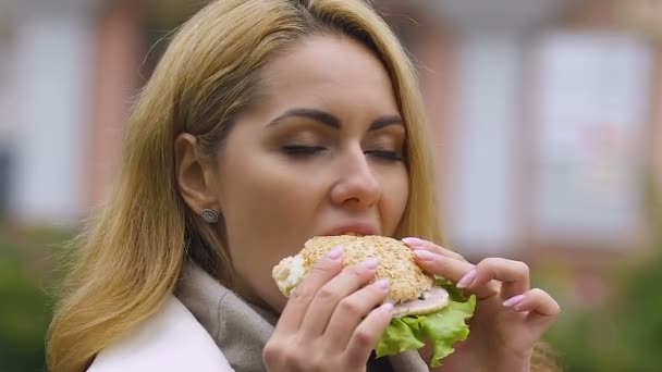 Mladá krásná dáma jíst hamburger, poškození nezdravé jídlo, trávení problémy rizika - Záběry, video
