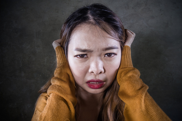 νέοι τρελός απελπιστική και θλιβερή Ασιατική Κορεάτικη γυναίκα που κρατά το κεφάλι κατάθλιψη και αναστατωμένος αίσθημα αγωνίας και πόνου στις απομονωμένες σκούρο φόντο σε πόνο έκφραση προσώπου που πάσχει κατάθλιψη - Φωτογραφία, εικόνα