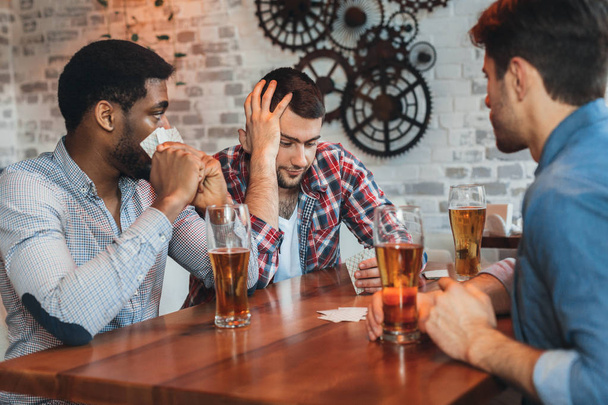 Мультикультурные мужчины играют в карты, отдыхают в баре
 - Фото, изображение