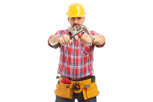 Constructor hábil sosteniendo en las manos martillo cruzado y llave aislada sobre fondo blanco estudio
 - Foto, Imagen