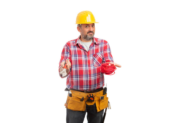 Constructor con expresión confusa sosteniendo cuerda roja y llave inglesa en manos aisladas sobre fondo blanco del estudio
 - Foto, Imagen