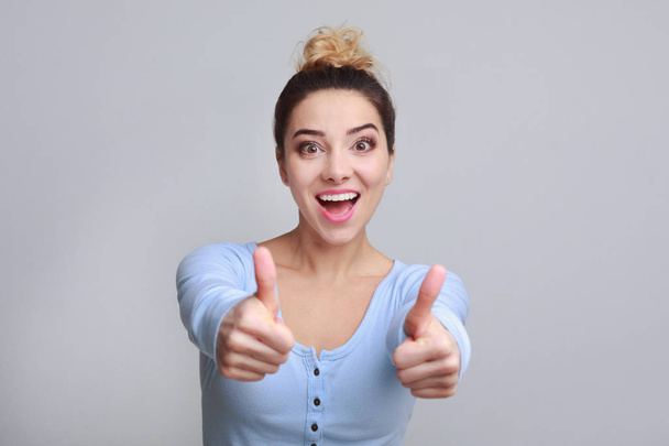 Excited woman showing thumbs up, grey background - Foto, Imagen