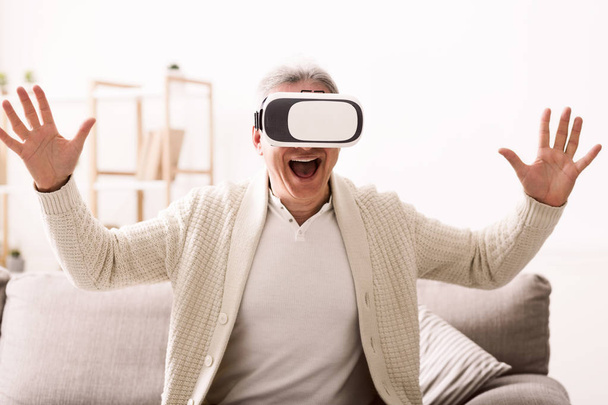 Пенсионер с виртуальной гарнитурой играет дома в видеоигру
 - Фото, изображение