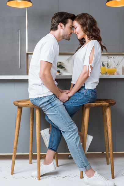 cheerful couple smiling with closed eyes while holding hands in kitchen  - Foto, afbeelding