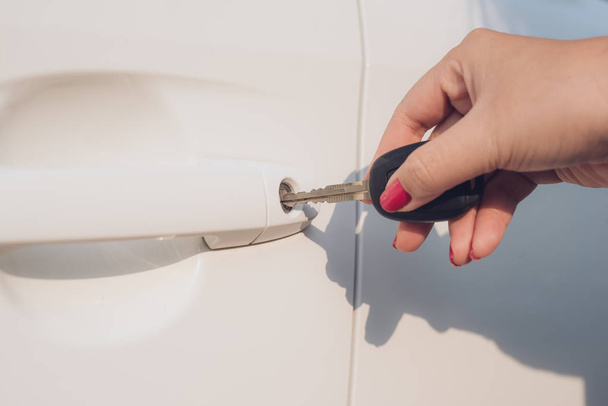 Женщина с крупным планом держит ключ, открывая дверь машины
. - Фото, изображение