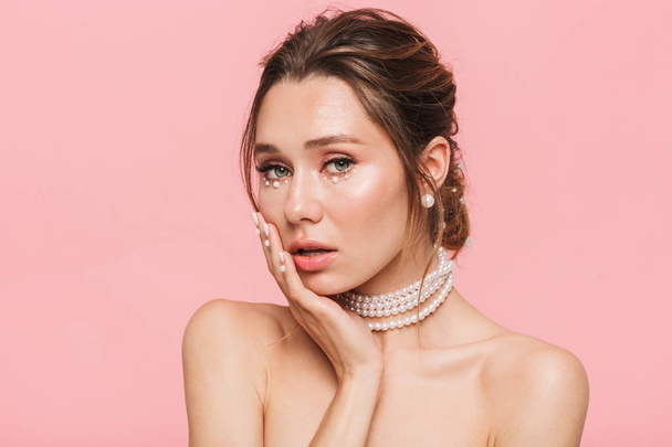 Beauty portrait of an attractive young topless woman posing isolated over pink background, wearing white pearl necklace - Φωτογραφία, εικόνα