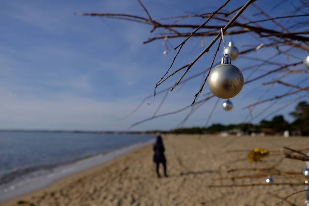decorazione natalizia in spiaggia in una giornata di sole con donna sfocata a piedi
 - Foto, immagini