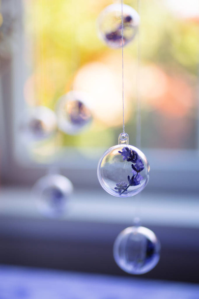 Flores de lavanda penduradas em bolas transparentes perto de janela ensolarada interior no verão. Decoração natural. Fundo embaçado sazonal
. - Foto, Imagem