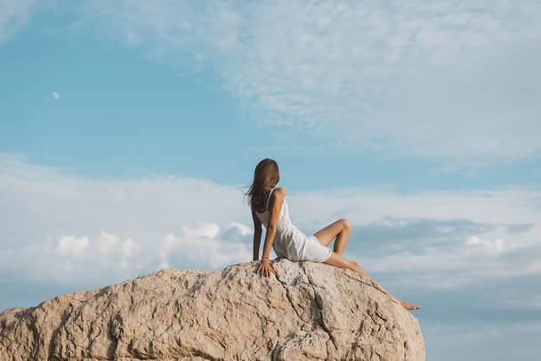 niña sentada en la roca, vista trasera
 - Foto, imagen