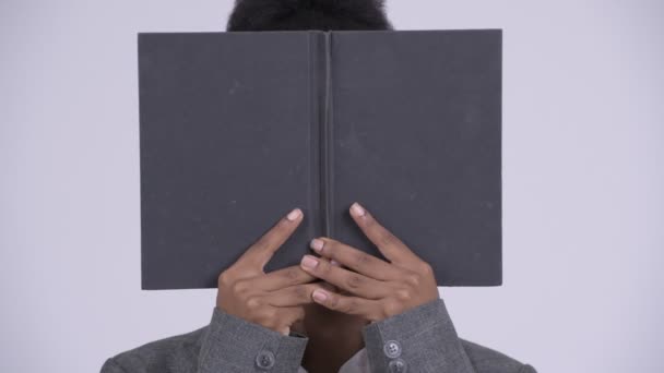 Face of young shy African businesswoman covering face with book - Filmati, video
