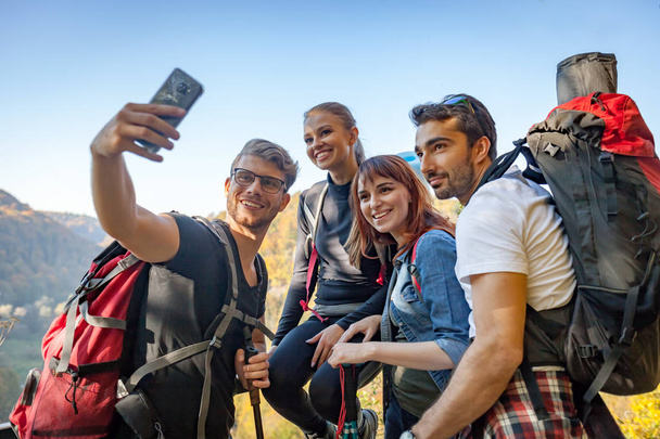 Friends with backpacks making selfie photo together at the peak of mount, travel and tourism concept - Foto, imagen