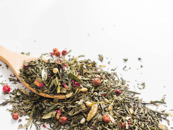 Dry leaves of Sencha green flower tea with cowberry leaf, red currant, Jasmine, rose petals, honey granules, forest berry aroma on white background - Фото, зображення