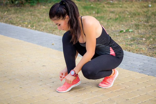 Young fitness girl ties up sneakers laces preparing for training working-out outdoor - Photo, Image