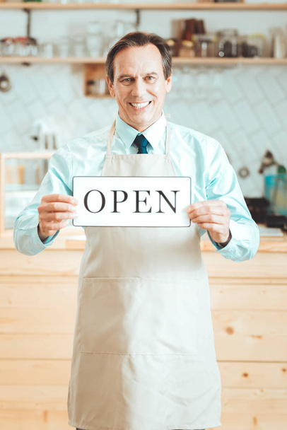 Smiling man standing with nameplate open - Foto, imagen