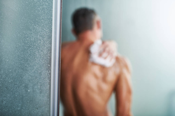 Shower door with young man washing himself on blurred background - Photo, Image