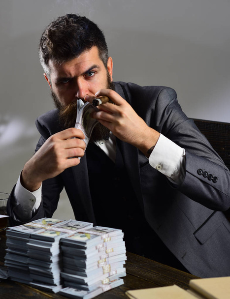 Money and power. Business and finance. Bearded man count dollars while smoking cigar. Successful businessman hold cash money. Rich man with beard in formal wear. Growing a business - 写真・画像