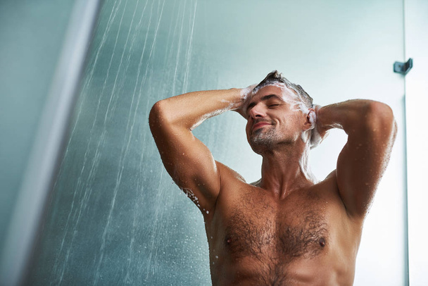 Handsome young man with beautiful body washing his hair - Valokuva, kuva