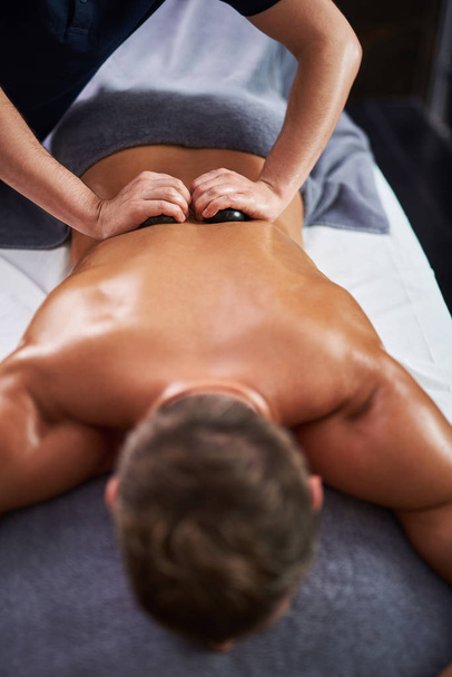 Young man lying on massage table during spa procedure - Fotografie, Obrázek