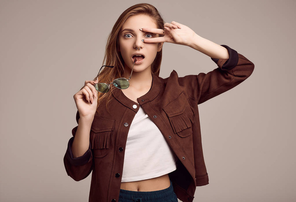 Retrato de menina adolescente bonito na jaqueta de moda e óculos posando em fundo cinza. Estúdio
. - Foto, Imagem