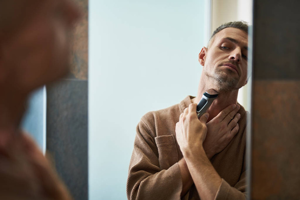 Handsome young man shaving with electric razor - Фото, зображення
