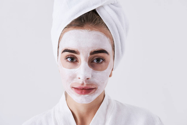 Cute girl with purifying mask on her face standing against white background - Фото, изображение