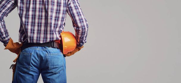 Builder man in plaid shirt and gloves wearing and holding helmet - Foto, imagen