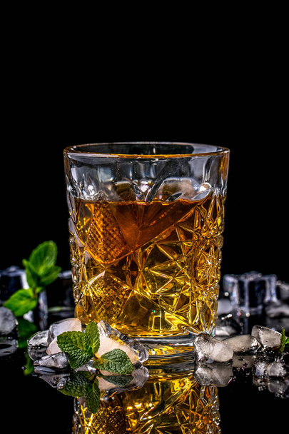 Kristal bardak viski, brendi ya da viski, buz ve siyah arkaplanda taze nane şekeri.. - Fotoğraf, Görsel