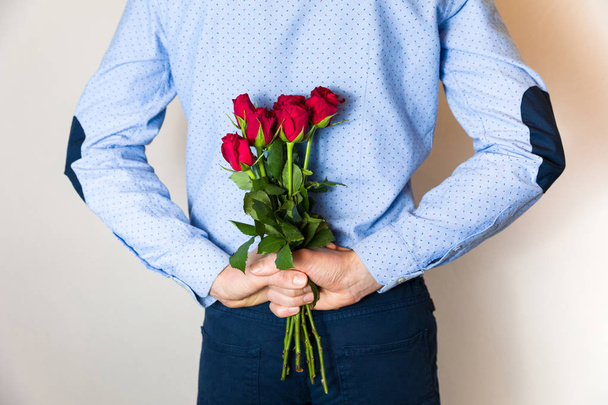 Romantické dárky překvapení, muž schovává přítomen, dar a drží červené růže, pár láska, Valentýn, Zenske den romantický vztah, 8 březen. - Fotografie, Obrázek
