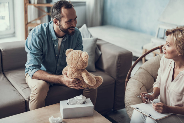 Happy man with teddy bear smiling to his psychologist - Fotoğraf, Görsel