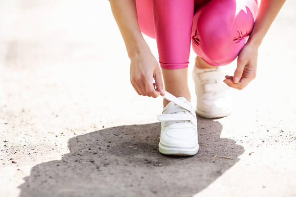 Sneakers probleem. Vrouwelijke Runner koppelverkoop haar schoenen voorbereiden voor een jog - Foto, afbeelding