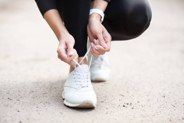 Sneakers probleem. Vrouwelijke Runner koppelverkoop haar schoenen voorbereiden voor een jog - Foto, afbeelding