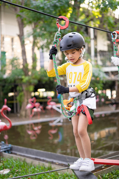 Gelukkig schoolmeisje genieten van activiteit in een avonturenpark  - Foto, afbeelding