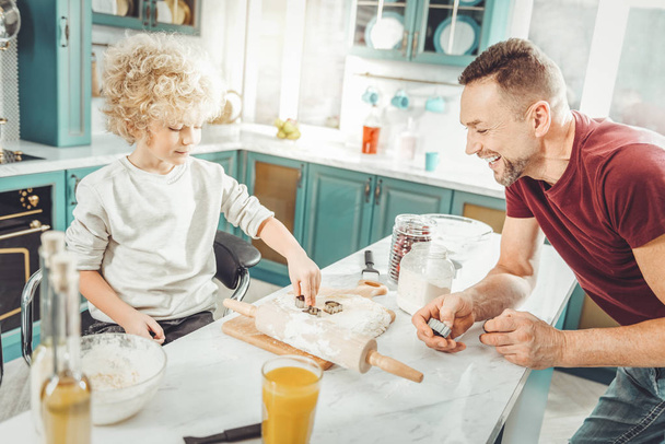 Handsome smiling man laughing while cooking with son - Photo, image