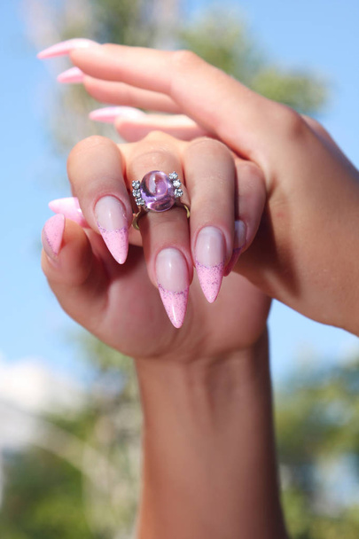 Довгий Французька нігтів з білим манікюр з боку жінки з рожевими аксесуар на тлі природи. - Фото, зображення