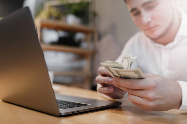 man with laptop and money on background. - Foto, afbeelding