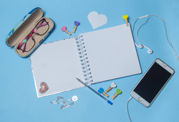 Top view workspace mockup on blue background with notebook, pen, coffee, clips and accessories. - Photo, image