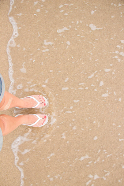 Vue de dessus, pieds debout sur le sable et vagues ondulantes
 - Photo, image