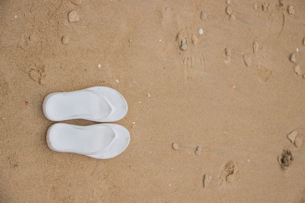 Fehér női papucs fekszenek a homokon a tenger - Fotó, kép