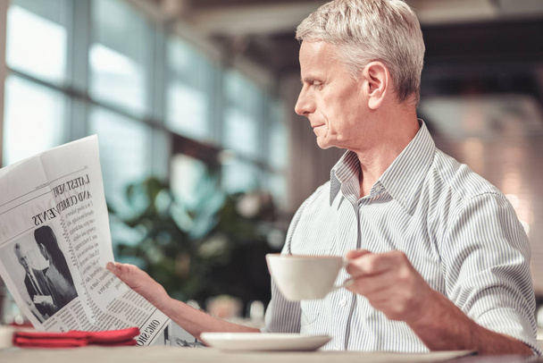 Attentive man reading a newspaper in a cafe - Fotó, kép