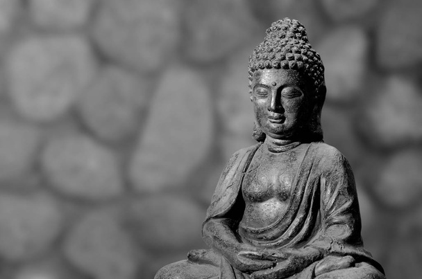 Boeddhabeeld zittend in meditatie houding tegen onscherpe achtergrond. - Foto, afbeelding
