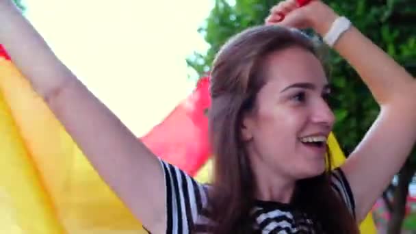 Slow motion of young happy woman cheering for Spain with the Spanish flag in hands. Young woman watching football match at outdoors match. - Metraje, vídeo