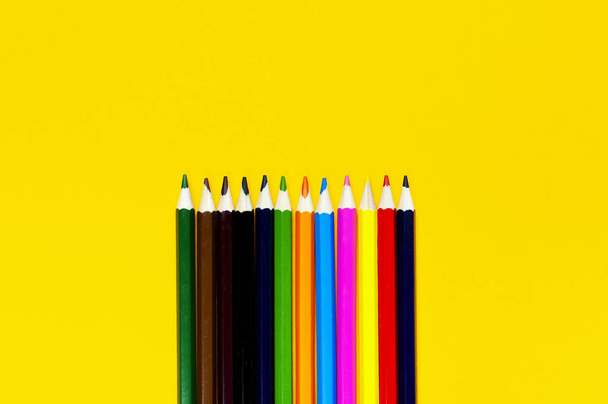 Color pencils on bright yellow background top view flat lay with copy space. Wooden colored pencils for drawing, objects for creativity, school supplies close-up. Back to school concept - Foto, Imagen