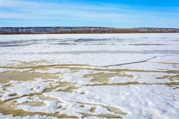 Толстый лед на реке разваливается на куски под воздействием теплых весенних лучей солнца
 - Фото, изображение