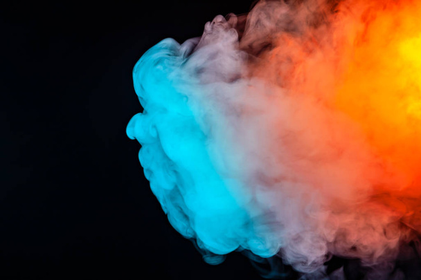 Uma espessa nuvem de fumaça na forma de uma água-viva é destacada como um arco-íris em cores diferentes em um fundo preto, girando em ondas para cima evaporando
. - Foto, Imagem
